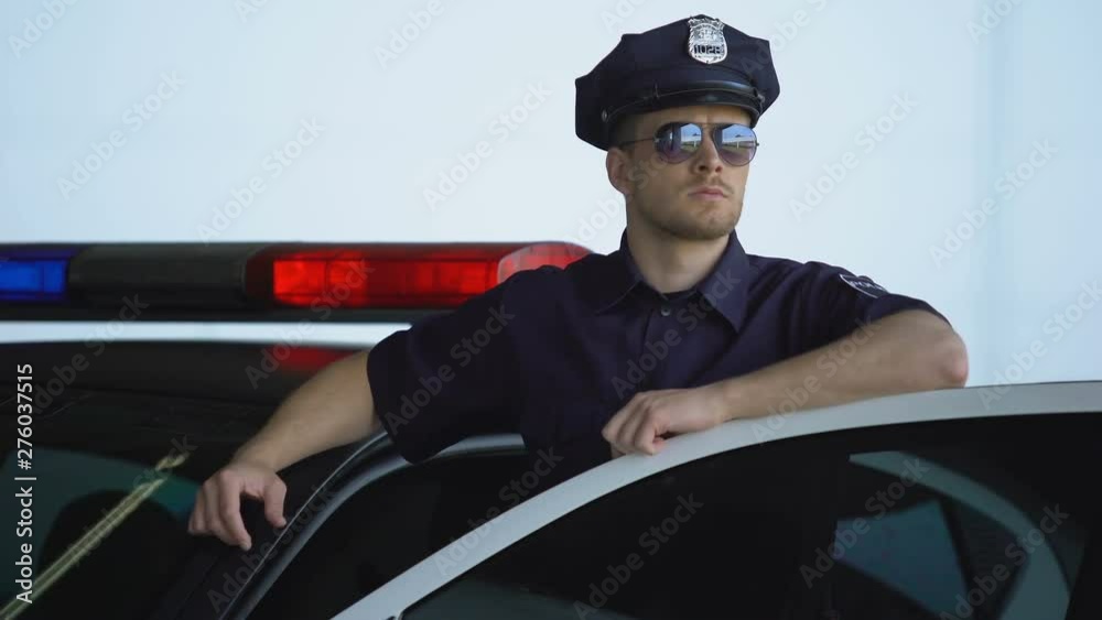 Brave policeman in uniform and sunglasses getting out from patrol car, duties