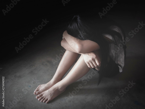 Teenage girl crying sitting on the floor with a grunge darkness background photo