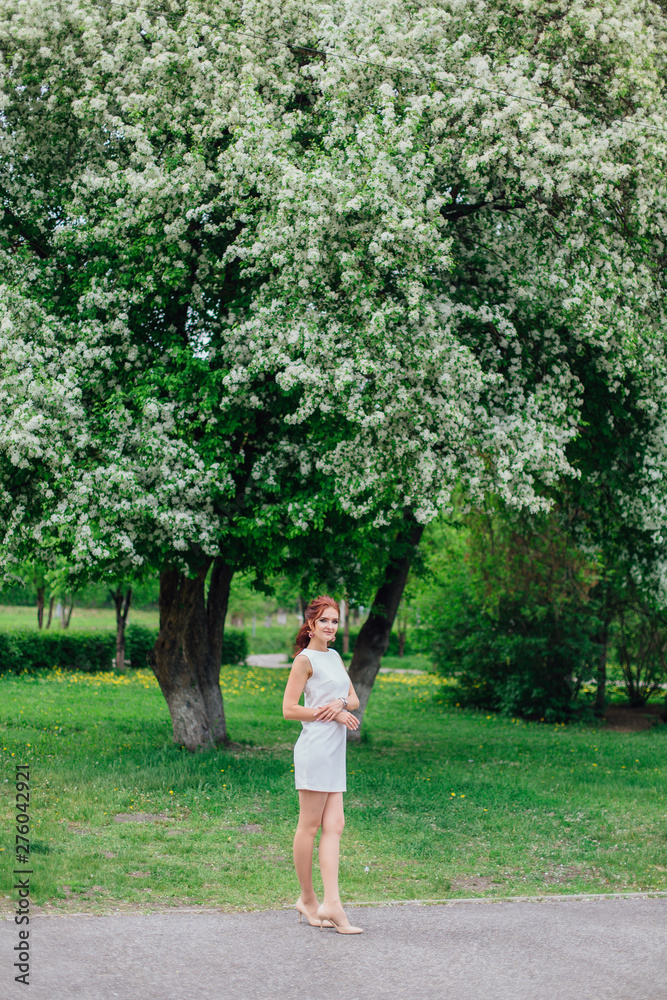 Charming woman wearing beautiful white dress under the apple tree Charming woman wearing beautiful white dress under the apple tree