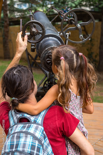 Education concept. Telescope. Father and daughter looking into big vintage telescope or watching a  kaleidoscope. 
