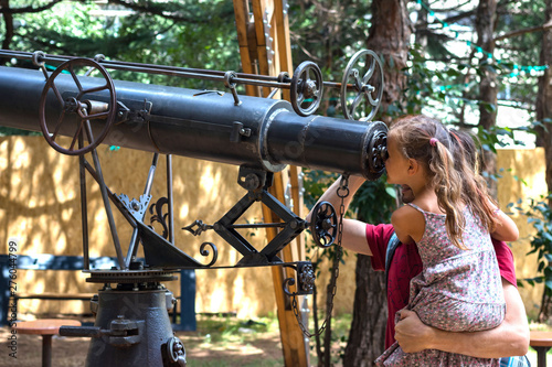 Education concept. Father and daughter looking into big vintage telescope or watching a kaleidoscope. New learnings and knowledges concept. 