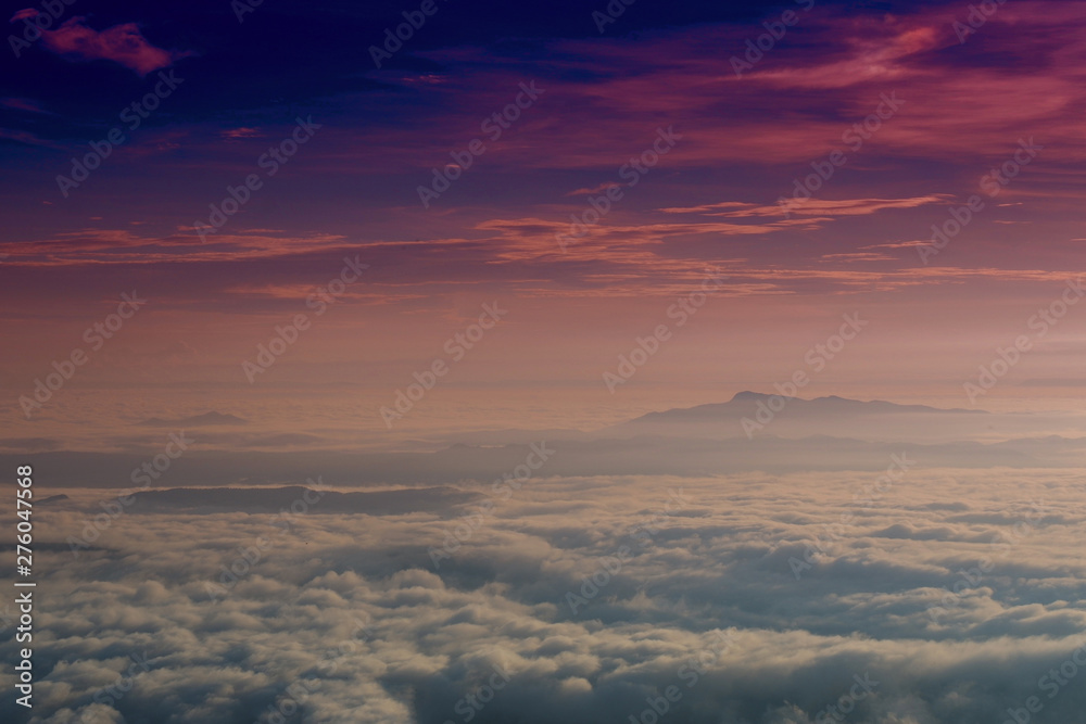 Sunrise foggy mist covered mountain forest landscape with dark purple sky background