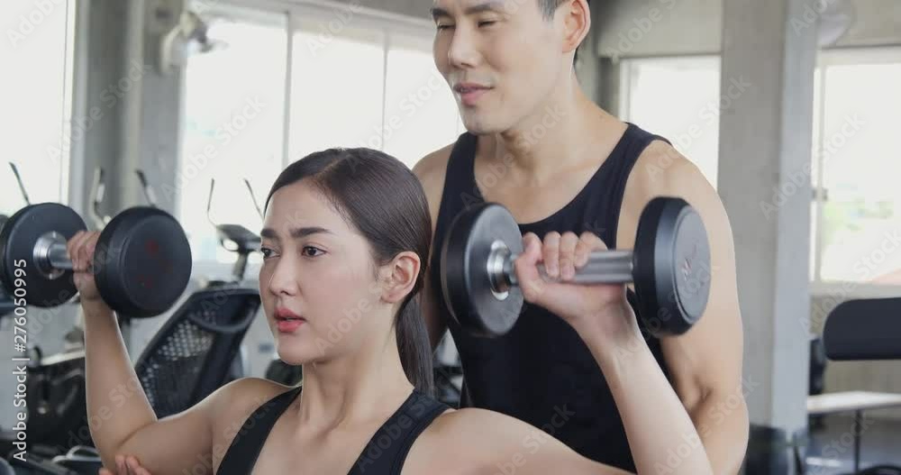 Young sexy woman doing exercise at a gym with her personal trainer. Healthcare and sports concept. Young sexy woman doing exercise at a gym with her personal trainer. Healthcare and sports concept.