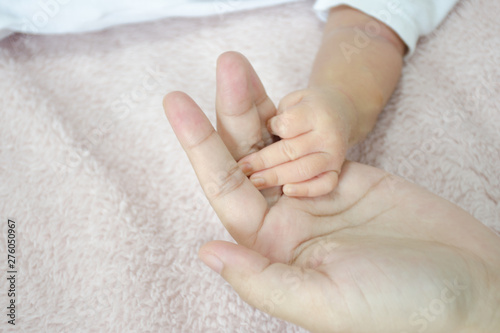 Baby's hand on mother's palm over soft fur background