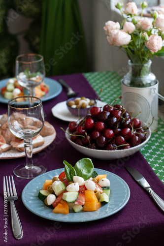 A gourmet lunch for two: a salad, fresh cherries and various appetizers.