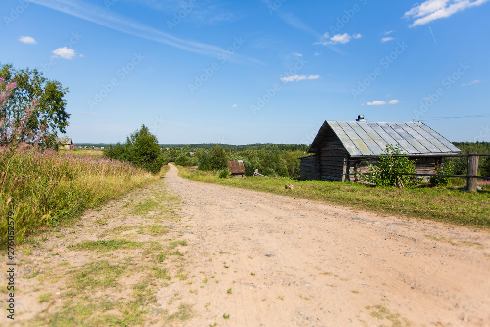 Wooden house and country road, rural landscape. Remote village in Karelia Republic, Russia.
