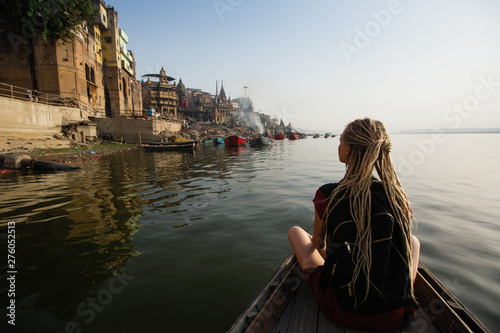 Tourist woman on a boat glides through the water on the Ganges river, Varanasi, India.