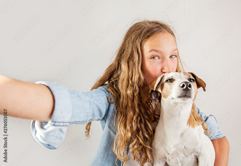 Smiling teen with dog making selfie photo on smartphone over white ...