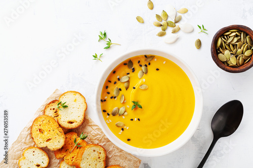 Photo Diet autumn pumpkin or carrot cream soup in bowl served with seeds and crouton on stone table from above