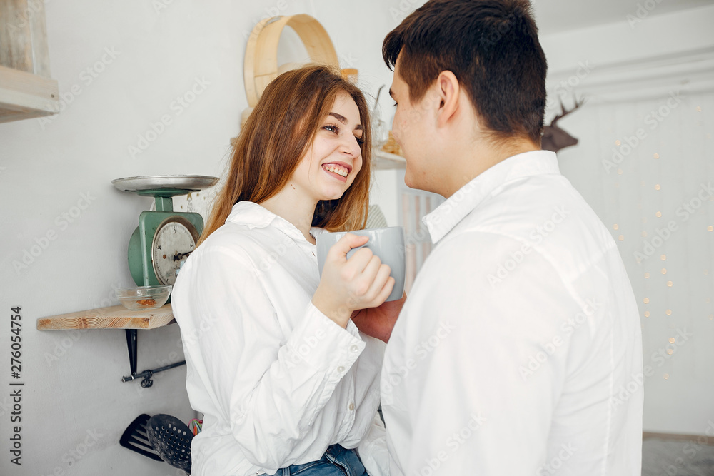 Fototapeta premium Cute couple in a kitchen. Lady in a white shirt. Pair at home