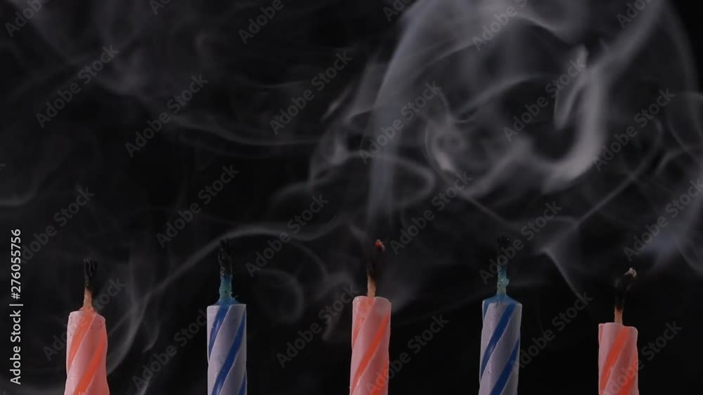 blowing out five birthday candles and smoke rising from the wick on black background 