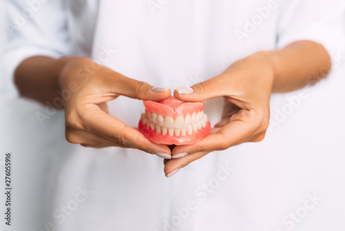 The dentist is holding dentures in his hands. Dental prosthesis in the hands of the doctor close-up. Front view of complete denture. Dentistry conceptual photo. Prosthetic dentistry. False teeth © MISHA