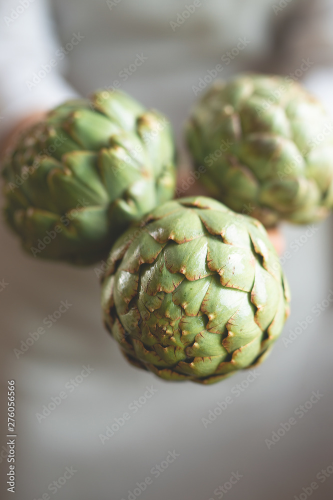 Obraz premium The girl is holding an artichoke in her hands. A concept of proper and dietary nutrition, Dotex