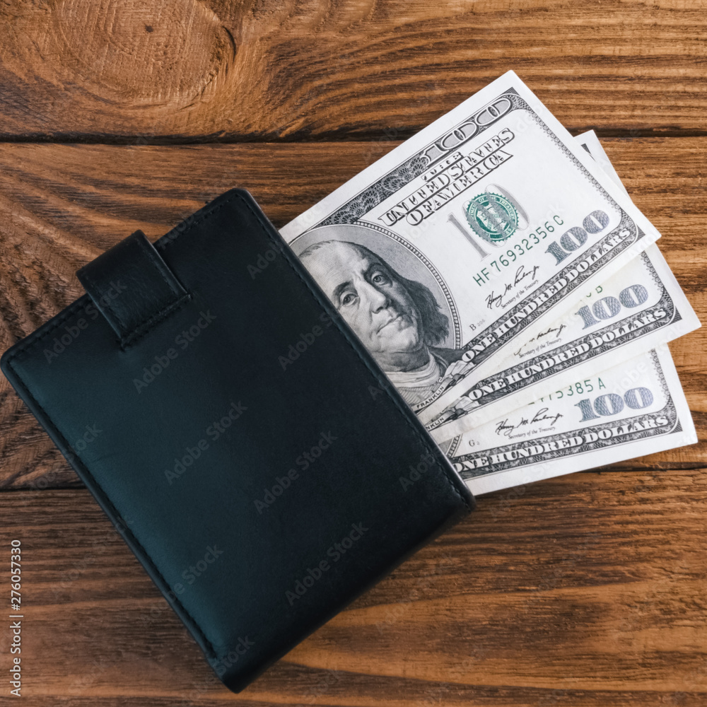 On wooden boards, textured wallet with one hundred dollar bills. On wooden boards, textured wallet with one hundred dollar bills.
