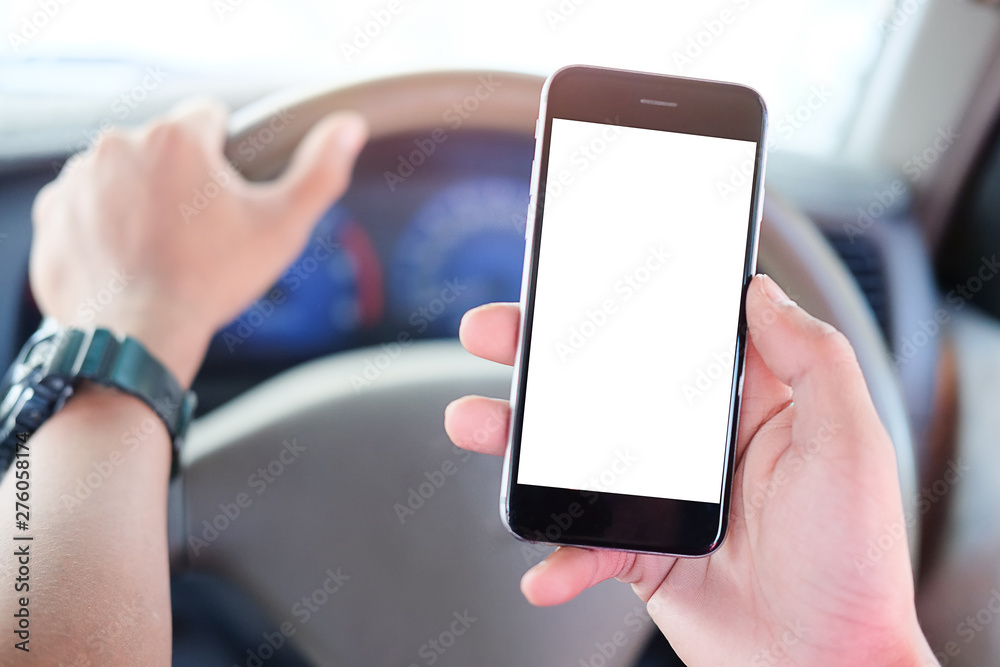 Cropped shot view The driver uses the phone while driving. Modern smart phone with round edges. Isolated screen for mockup. Car navigation display in background. Cropped shot view The driver uses the phone while driving. Modern smart phone with round edges. Isolated screen for mockup. Car navigation display in background.