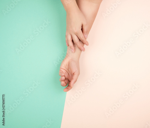 two female hands with light smooth skin on a green pink background