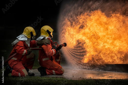 2 firefighters spraying water in fire fighting operation, Fire and rescue training school regularly to get ready