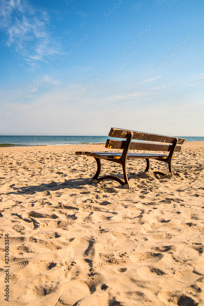bench on a lonesome beach of the Baltic Sea with blue sky