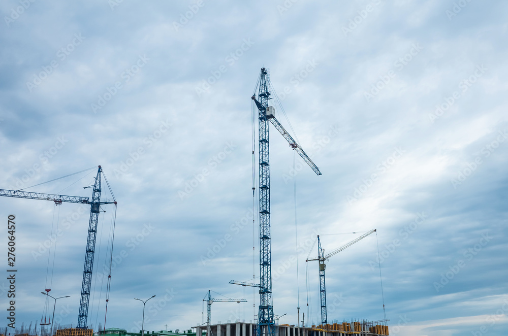 Construction cranes on a cloudy sky background. The concept of building houses, urban development. Place for text, background image. Cityscape. Construction cranes on a cloudy sky background. The concept of building houses, urban development. Place for text, background image. Cityscape.