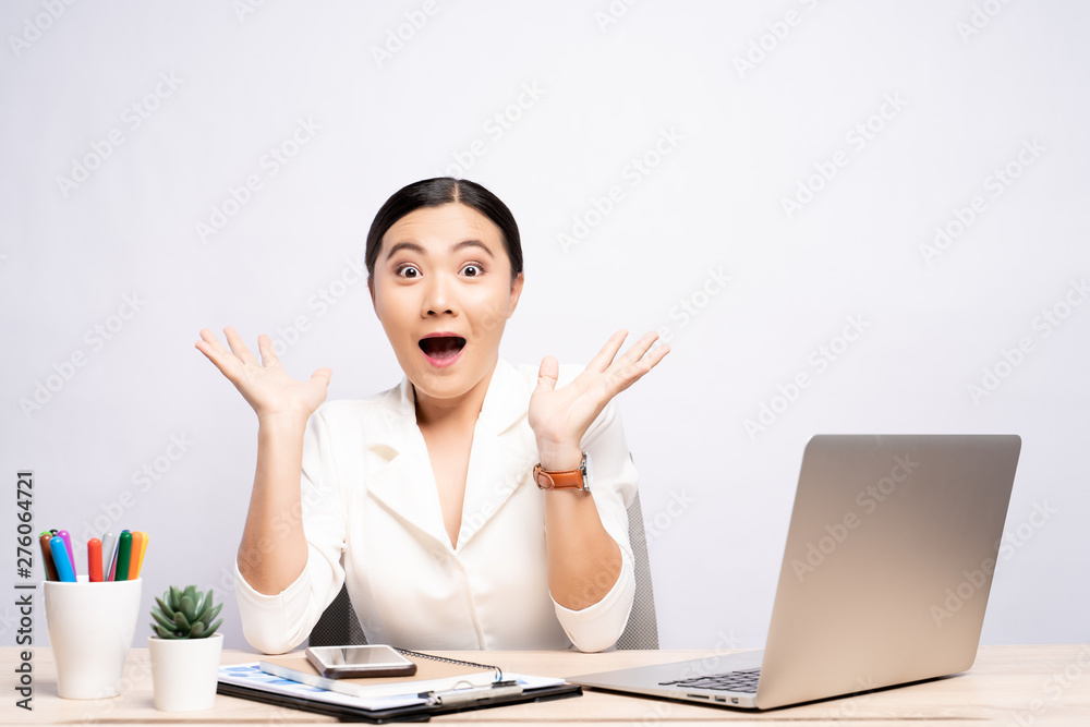 Portrait of a excited woman sitting at office isolated over background Portrait of a excited woman sitting at office isolated over background