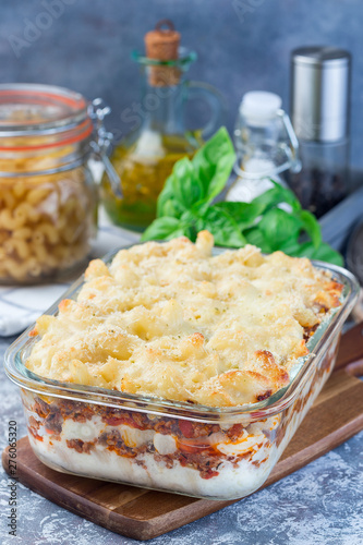Macaroni casserole with ground beef, cheese and tomato in a glass baking dish, vertical