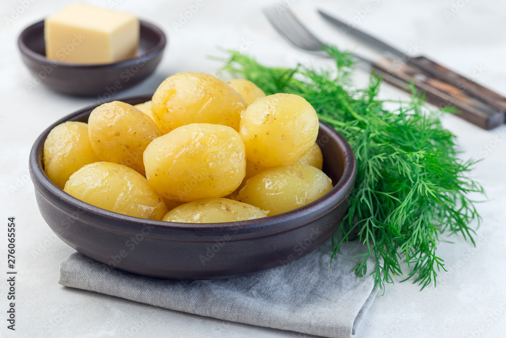 New young boiled potato topped with melted butter in ceramic bowl and dill on background, horizontal New young boiled potato topped with melted butter in ceramic bowl and dill on background, horizontal