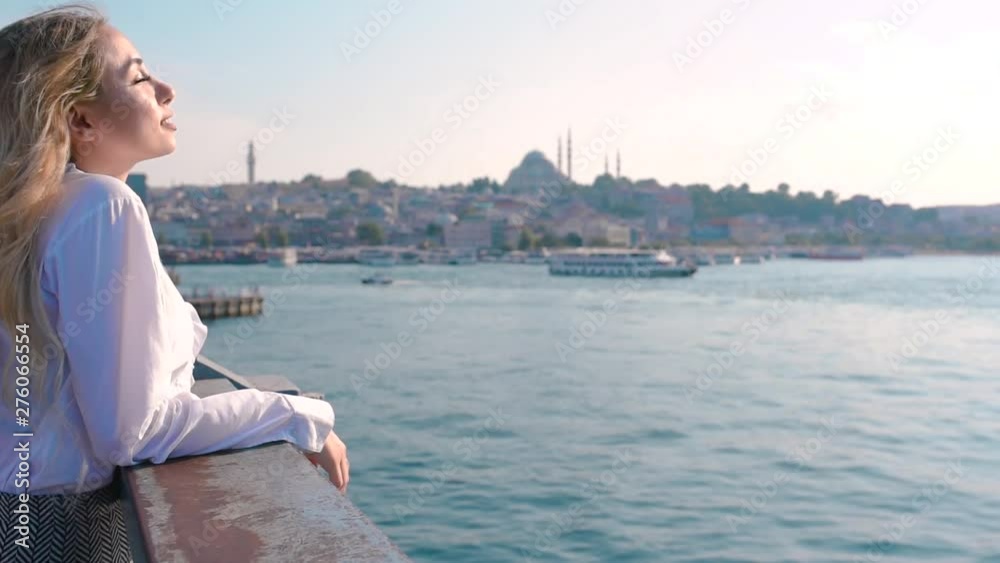 Ultra Slow Motion:Beautiful girl stands over Galata Bridge and enjoys view of bosphorus in Istanbul,Turkey.Traveler concept