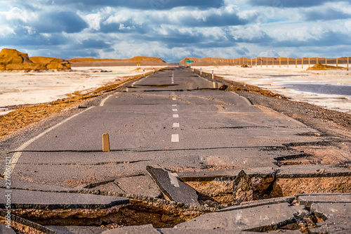 .broken asphalt road with cloudy sky in the middle of the  Lut desert,hottest desert in the world, also known like Kalut Desert