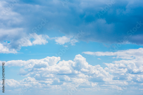Beautiful white cumulonimbus clouds against the background of the bright blue sky © chernikovatv