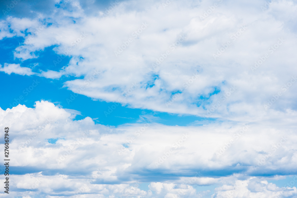 Fototapeta premium Beautiful white cumulonimbus clouds against the background of the bright blue sky