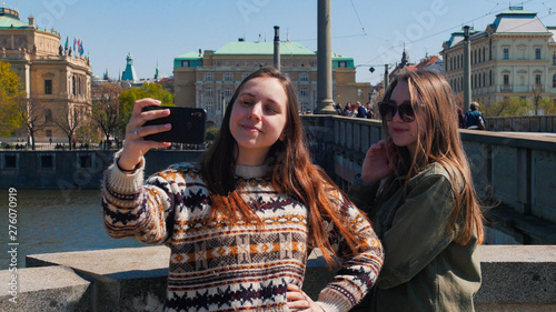 Two young women standing on bridge and take a selfie. Czech, Prague photo