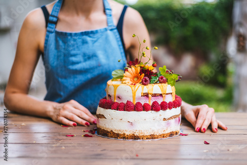 Foto Naked rustic cake with strawberries and white cream in front of young female  pa