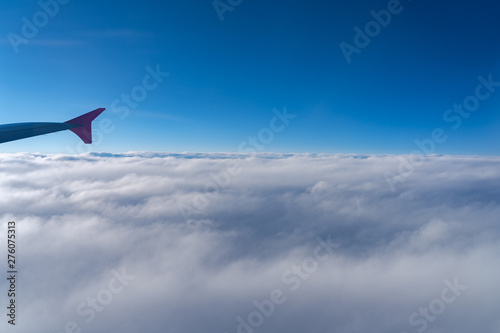 Up in the air, view of aircraft wing silhouette with dark blue sky horizon and cloud background in sunset time, viewed from airplane window