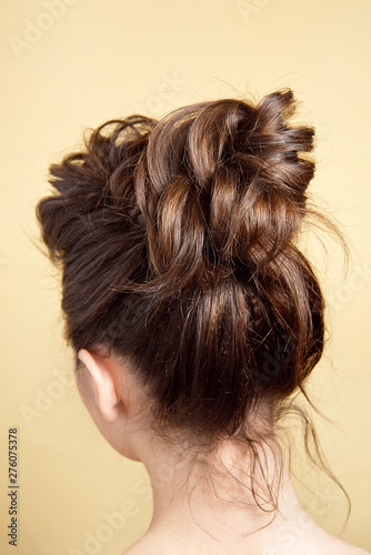 Rear view of female hairstyle medium bun on long straight brown hair with radical volume