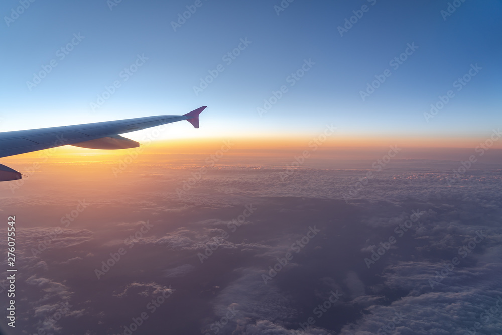 Up in the air, view of aircraft wing silhouette with dark blue sky horizon and cloud background in sunset time, viewed from airplane window Up in the air, view of aircraft wing silhouette with dark blue sky horizon and cloud background in sunset time, viewed from airplane window