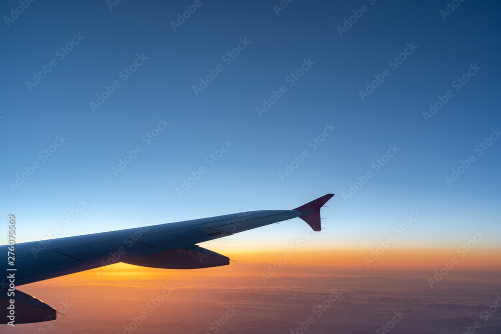Up in the air, view of aircraft wing silhouette with dark blue sky horizon and cloud background in sunset time, viewed from airplane window Up in the air, view of aircraft wing silhouette with dark blue sky horizon and cloud background in sunset time, viewed from airplane window