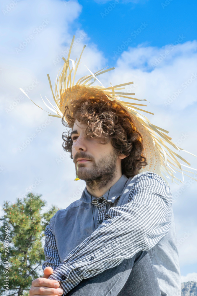 Jeune homme adulte regardant au loin, cheveux bruns frisés avec un chapeau  de paille antillais sur la tête Stock Photo | Adobe Stock