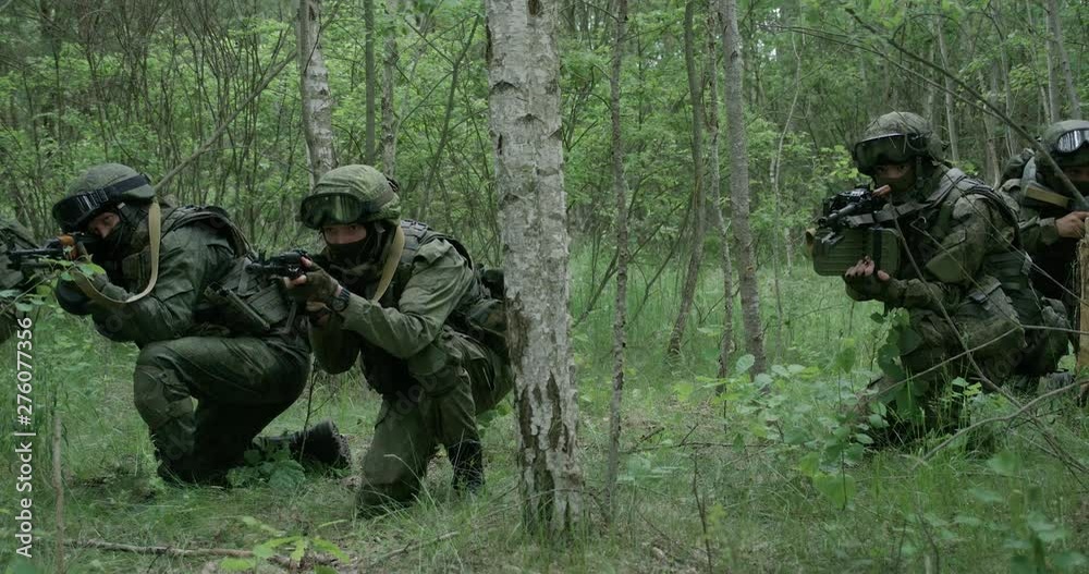 Soldiers in camouflage with assault rifle walking through the forest, military action in the woods, 4k slow motion. Soldiers in camouflage with assault rifle walking through the forest, military action in the woods, 4k slow motion.