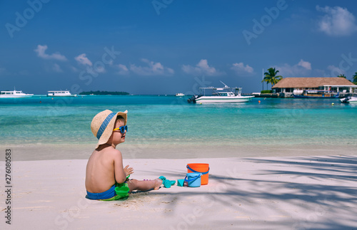 Fototapeta Naklejka Na Ścianę i Meble -  Three year old toddler boy playing with beach toys on beach.  Summer family vacation at Maldives.