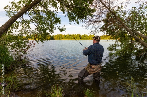 Angler catching the fish in the lake during summer day