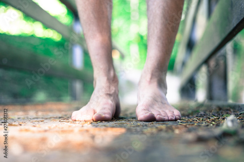 Forest adventure: Closeup of barefoot male feet on a wooden bridge in the woodland
