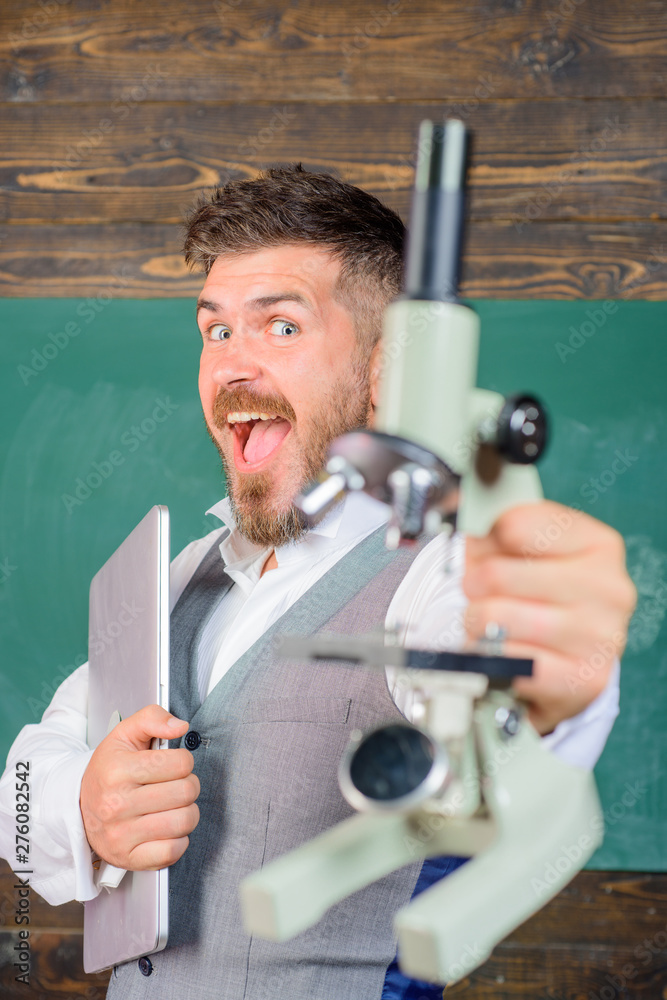 Bearded man with notebook and microscope. Biology or chemistry. College teacher with computer and microscope. Excited tutor in classroom. Happy scientist with laptop and microscope. Selective focus. Bearded man with notebook and microscope. Biology or chemistry. College teacher with computer and microscope. Excited tutor in classroom. Happy scientist with laptop and microscope. Selective focus.