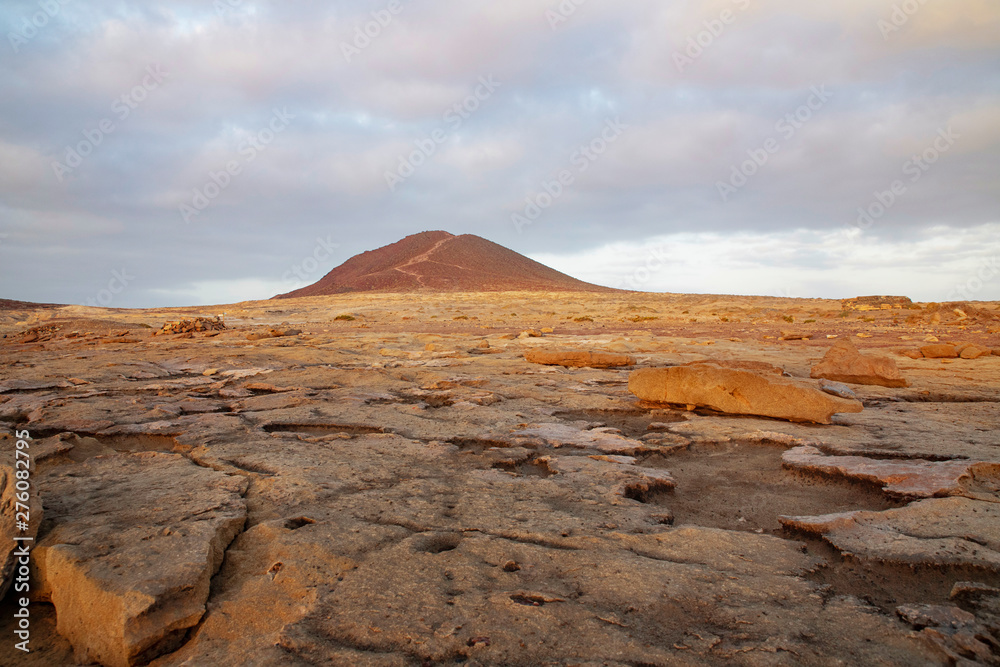 Overcast sunrise over Montana Roja Special Natural Reserve, an unusual volcanic cone, one of the best samples of inorganic sand habitats on the island, in El Medano, Tenerife, Canary Islands, Spain