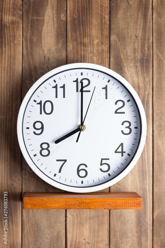 wall clock at shelf on wooden background
