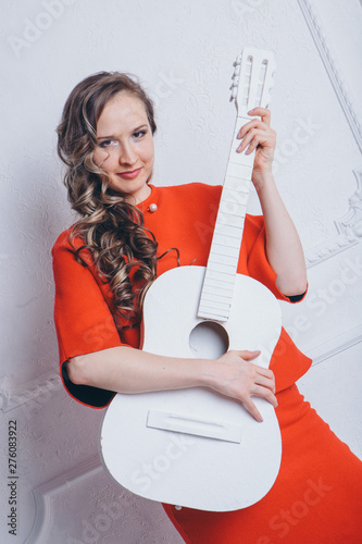 businesswoman in a red suit with a white guitar in his hands on a white background. Musician with an instrument in his hands photo