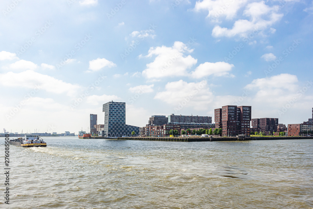 Fototapeta premium A cargo boat on the river Maas passes the building of the Netherlands Maritime University