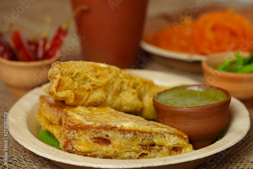 Sandwich Bread Pakora / pakoda (triangle shape) served with tomato ketchup, chutney, green chilli and onion slices, Popular indian tea-time snack