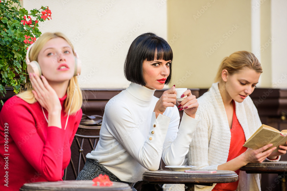 different ways to relax. girls in cafe. social diversity. listening music. reading book. drinking coffee. frienship. free time spending. relax. business meeting. three girls do different things different ways to relax. girls in cafe. social diversity. listening music. reading book. drinking coffee. frienship. free time spending. relax. business meeting. three girls do different things