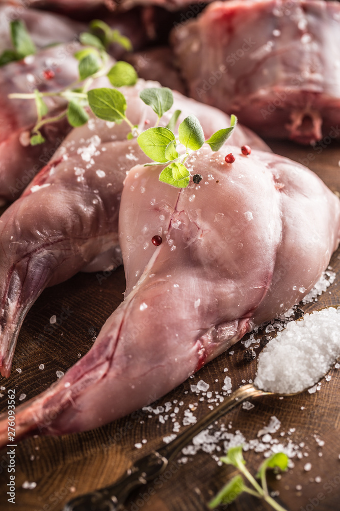 Fototapeta premium Raw rabbit legs salt pepper and herbs on butcher board