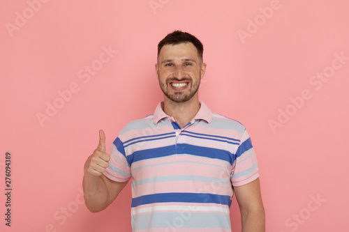 Portrait of an excited bearded man standing isolated over pink background, thumbs up.